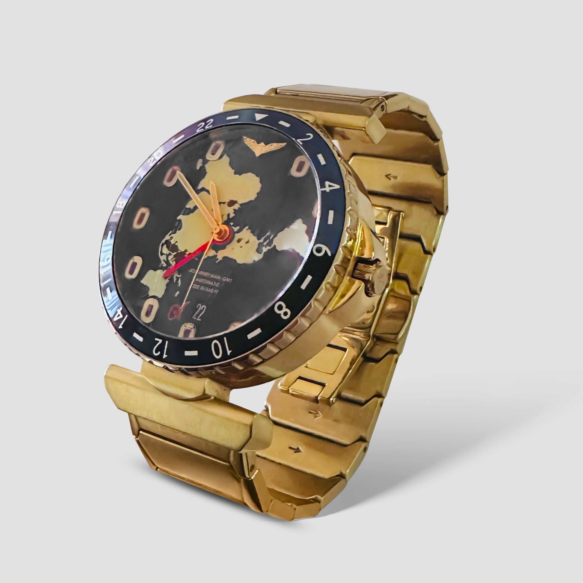 Journeyman GMT gold watch with world map dial, red GMT hand, brushed finish, and gold metal bracelet.