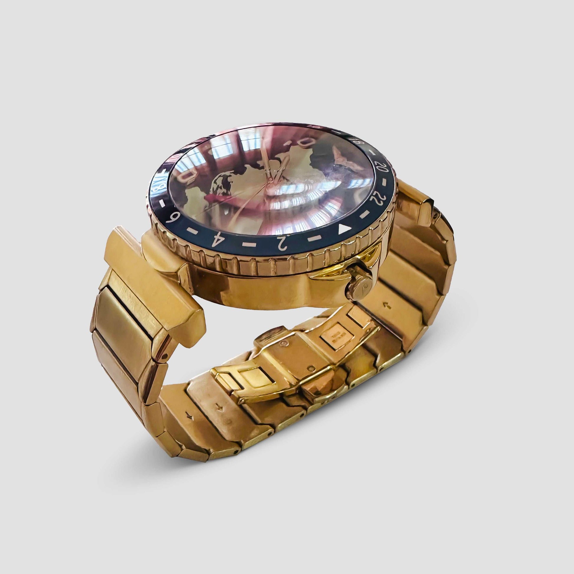 Gold Journeyman GMT watch with a world map dial, red GMT hand, airplane window hour markers, and a brushed finish on a metal bracelet